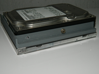 Figura 6 – Case para HD de 3,5” fabricado por impressão 3D em ABS, com o dispositivo montado, posicionado sobre uma caixa acrílica padrão de CD para fins de comparação dimensional